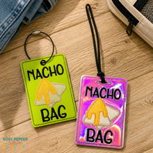 Load image into Gallery viewer, Two 'Nacho Bag' luggage tags on a wooden surface with denim and a bag in the background.